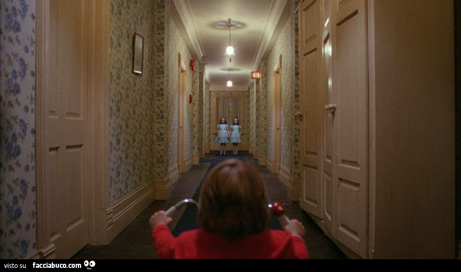 Il bambino va verso le gemelle nel corridoio di Shining