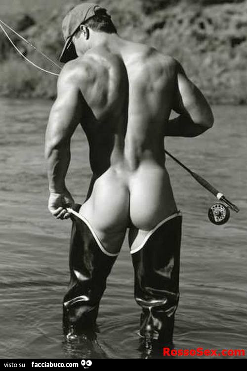 Uomo nudo con stivaloni dentro l'acqua che pesca