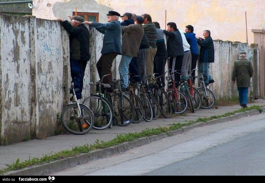 Anziani in piedi sulle biciclette per guardare oltre il muro
